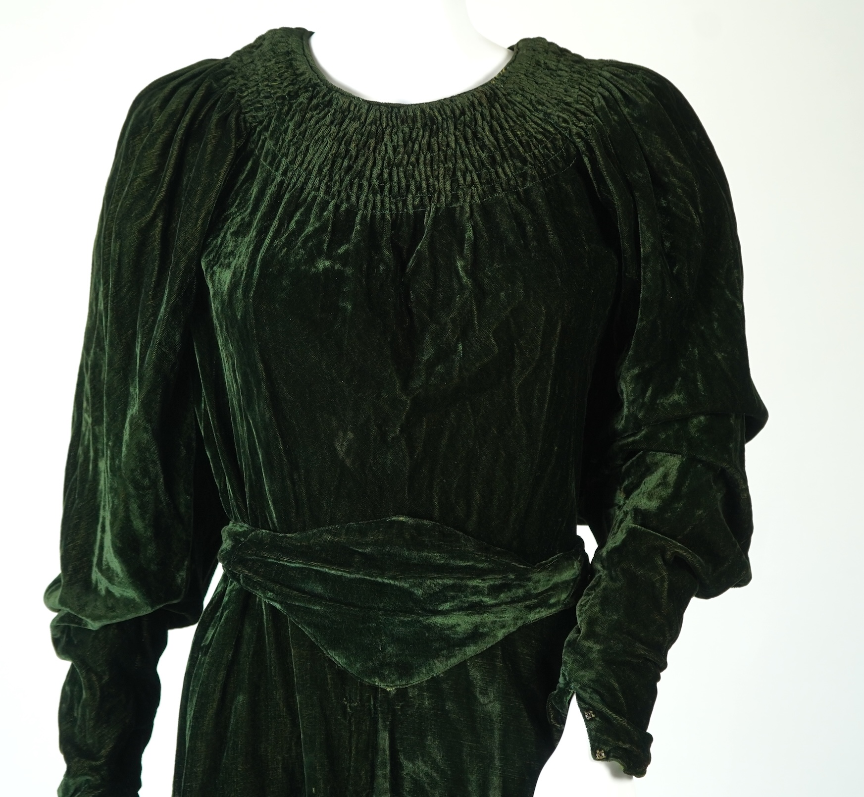 A flesh coloured 1930s lace evening dress and matching jacket together with a bottle green velvet evening dress and buckle belt and an unusual green shot silk pleated under skirt. Lace dress bust 32 inches. 156cm long. C